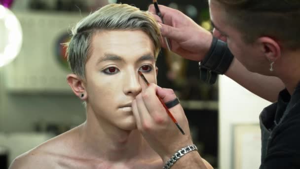 젊은 남자 근접 촬영을 위한 얼굴 예술을 만드는 메이크업 아티스트 — 비디오