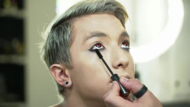 Makeupartist gör ansikte konst för en ung blond man — Stockvideo
