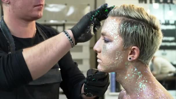 Maquillaje artista cubriendo jóvenes hombres pelo con los destellos de primer plano — Vídeo de stock