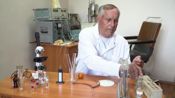 Пожилой профессор в белом работает с кровью в лаборатории — стоковое видео