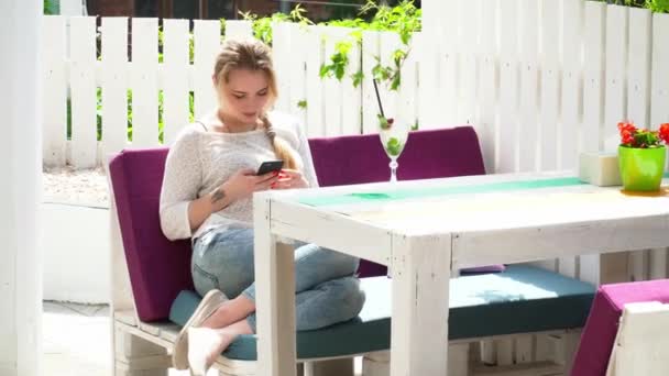 Ung kvinna med hennes mobiltelefon i sommarrestaurangen utomhus — Stockvideo