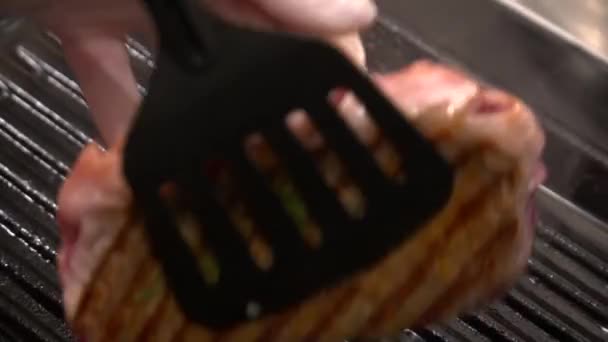 Κοντινό πλάνο του σεφ χέρια τηγανίσματος μπριζόλα στη σχάρα — Αρχείο Βίντεο