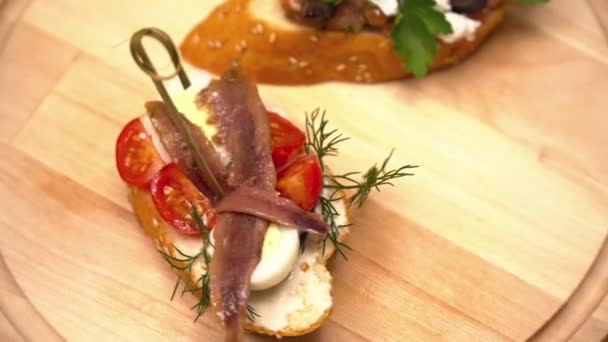 Тапас на деревянной доске с сыром и рыбой крупным планом — стоковое видео