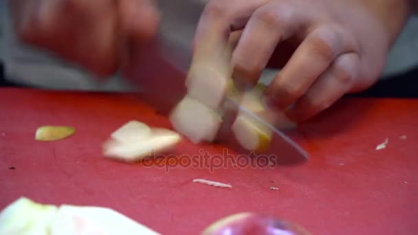 Близкий шеф-повар режет яблоко на красной доске — стоковое видео