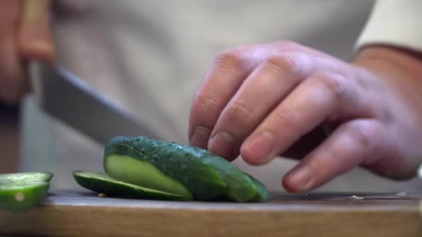 Chef coupant le concombre sur le plateau en bois avec le couteau — Video