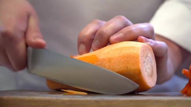 Kocken skär morot med kniven i styrelsen — Stockvideo