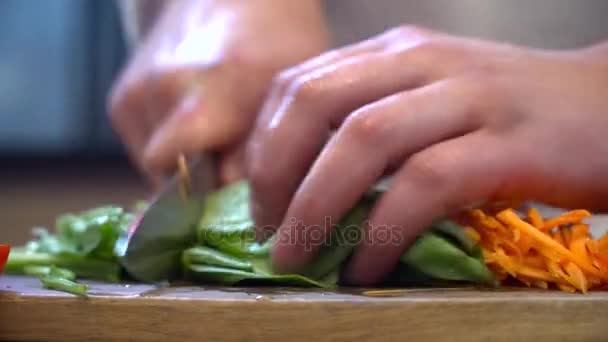 Крупним планом шеф-кухаря, що ріже шпинат на дерев'яній дошці — стокове відео