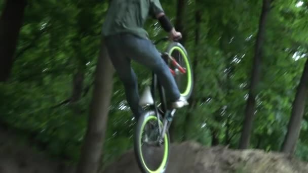 Homme dans le casque sautant à vélo dans la forêt ralenti gros plan 