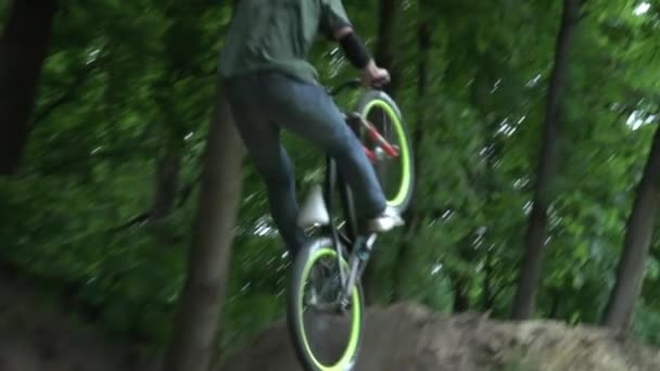 Hombre en el casco saltando en bicicleta en el bosque cámara lenta primer plano — Vídeos de Stock