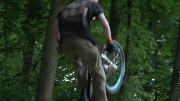 Gros plan de l'homme dans le casque sautant à vélo dans la forêt au ralenti 