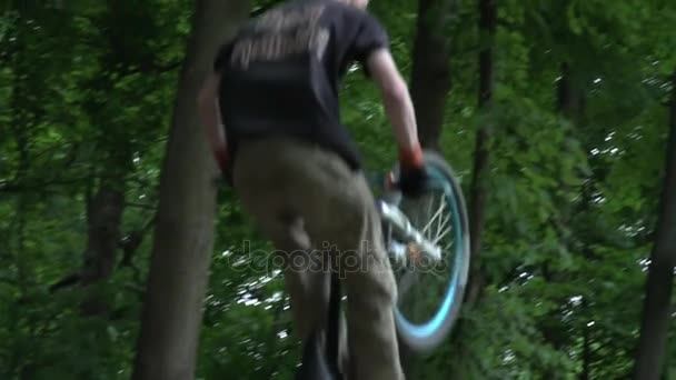 Primer plano del hombre en el casco saltando en bicicleta en el bosque cámara lenta — Vídeos de Stock