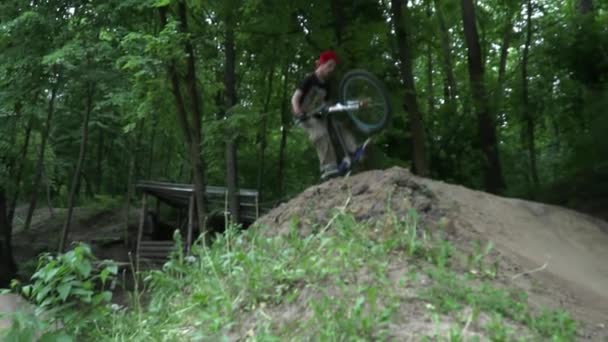 Hombre en el casco saltando en bicicleta moderna en el bosque cámara lenta — Vídeos de Stock