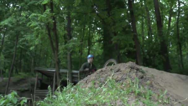 Jeune homme dans le casque sautant sur le vélo moderne dans la forêt au ralenti 