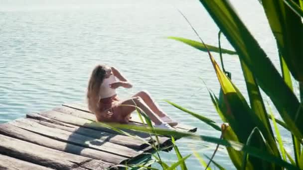 Ung kvinna avkopplande nära sjön under sommaren — Stockvideo