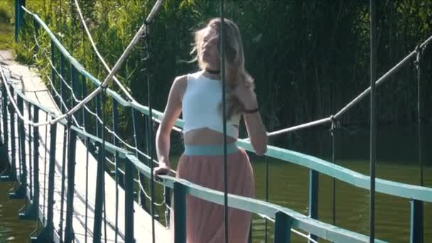 Joven hermosa mujer caminando en el puente colgante — Vídeo de stock