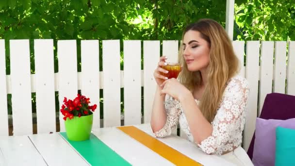 Bella donna in abito bianco seduta nel ristorante estivo e bere cocktail — Video Stock