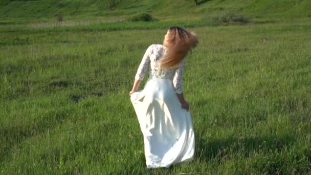 Beautiful young woman in white dress playing with hair on the meadow — Stock Video