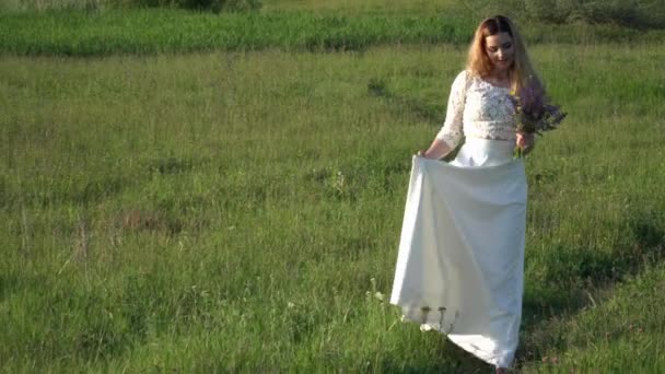 Hermosa joven mujer caminando en el prado con flores — Vídeos de Stock