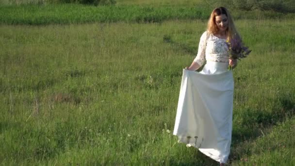 Mooie jonge vrouw lopen op de weide met bloemen — Stockvideo