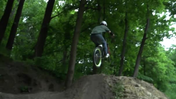 Joven en el casco saltando en bicicleta en el bosque cámara lenta — Vídeos de Stock