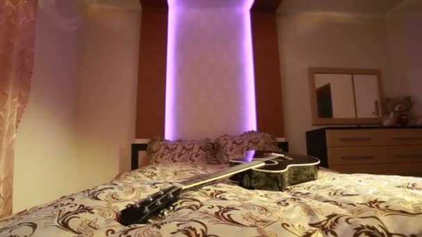 Guitarra deitada na cama no quarto — Vídeo de Stock