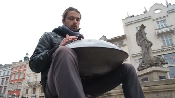 Young Street artist performing on the street. Performer with handpan or hang that is a traditional ethnic drum musical instrument the bottom corner — Stock Video