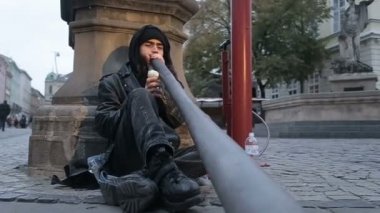 Bir sokak müzisyen didgeridoo, Kuzey Avustralya yerli Avustralyalılar tarafından geliştirilen bir üflemeli çalgı çalmaya.