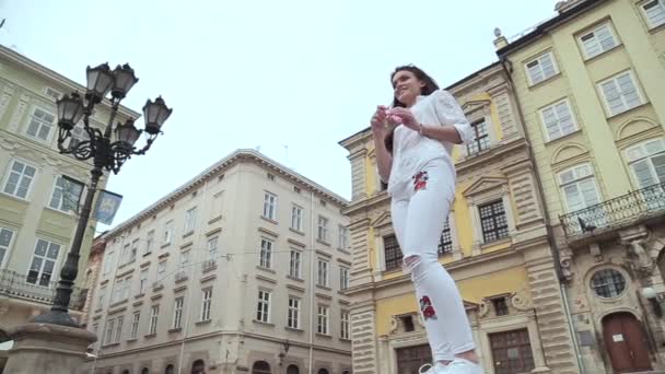 Schöne junge brünette Mädchen weht Seifenblasen in der Stadt lange Schuss — Stockvideo