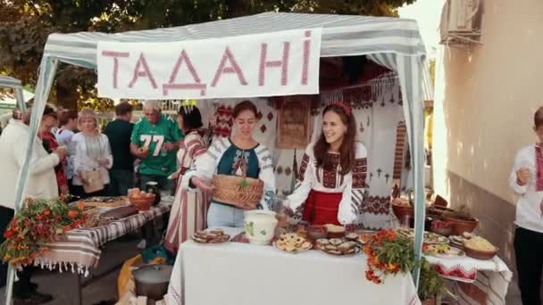 Красивые девушки в украинской традиционной одежде имеют бизнес на ярмарке — стоковое видео
