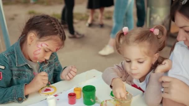 Duas crianças usam cores brilhantes pintura em peças de madeira ao ar livre . — Vídeo de Stock