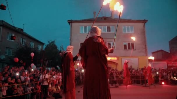 Stilt walkers start fire show with igniting bowls above ground. — Stock Video