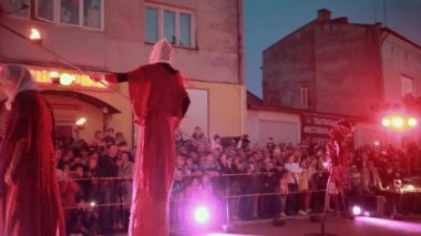 Stilt Walker 'lar kaseleri ateşe verdi, erkek oyuncu ortadaki meşaleyi yaktı