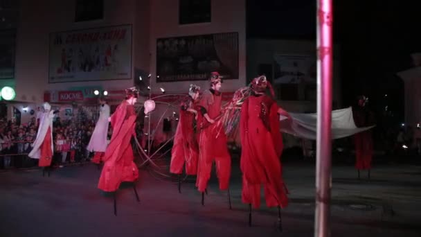 Kırmızı kostümlü Stilt Walker 'lar çubukların üstüne beyaz kumaş koydular.. — Stok video