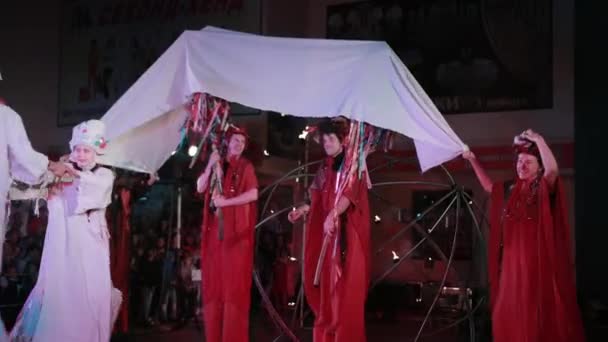 붉은 옷을 입고 걷는 사람들은 그 위에 흰 천으로 된 막대기를 들고 있다. — 비디오