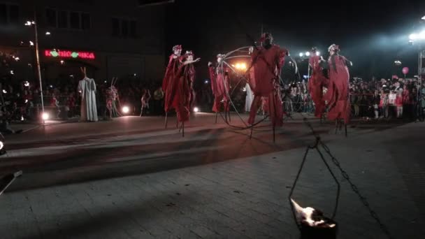 Perfect dancing of stilt walkers around metallic sphere at night fire show. — Stock Video