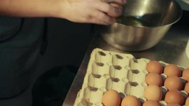 Kadın karton tutucudan yumurta alır, sarısını beyazdan ayırır..