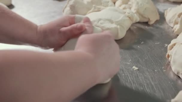 Des morceaux de pâte reposent sur une table de travail en acier inoxydable, le chef pétrit la pâte . — Video
