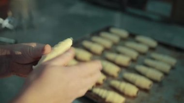 Dişi eller kruvasan yapıyor, sonra da bir tanesini fırın tepsisine koyuyorlar..