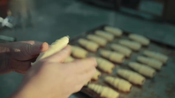 As mãos femininas estão fazendo croissant, em seguida, colocando um pronto na bandeja do forno . — Vídeo de Stock