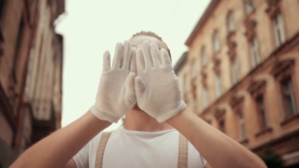 Mladý mime se schovává za ruce, pohybuje hlavou nad imaginární zdí. — Stock video