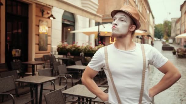 Jeune mime au regard audacieux et arrogant, appelle quelqu'un à se battre dans la rue près du café . — Video