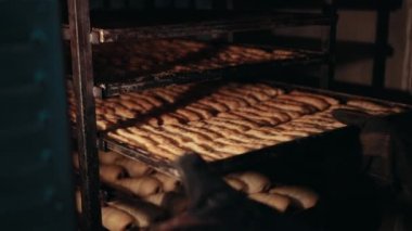Kadın fırıncı, raftan farklı türde hamur işleri alıyor..