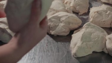 Bileğinde sos lekesi olan kadın elleri hamuru alır, sonra yoğurup yuvarlamaya başlar..