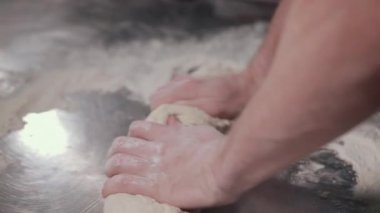 İnsan tarafından paslanmaz çelik masa üzerinde un içinde hamur ile çalışma süreci.