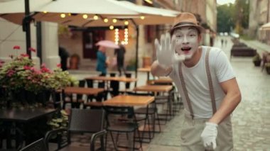 Pandomimci tanımaz, gülümser, el sallar, sevinçle bacak değiştirir..