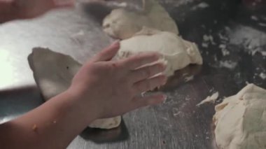 Kadın elleri paslanmaz çelik çalışma masasında mutfakta hamurla çalışıyor..