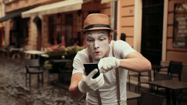 Schöner junger Mime zeigt auf sein Telefon, redet streng, beginnt dann zu streiten. — Stockvideo