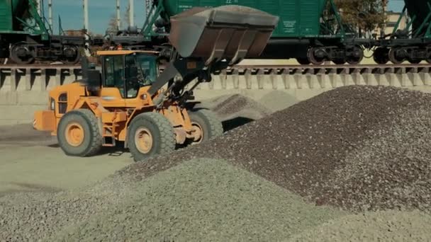 Strojní zařízení žlutého traktoru shromažďuje výrobek v jedné oblasti. — Stock video
