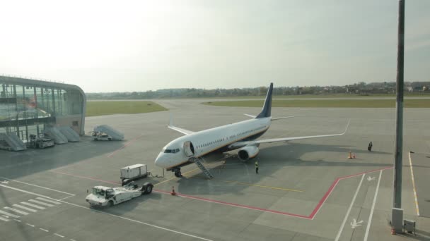 Ein Flughafenarbeiter steht auf der Landebahn, ein anderer verlässt mit Koffer das Gelände. — Stockvideo