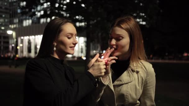 Concept of not healthy lifestyle. Brunette lights cigarette to red-haired friend — 图库视频影像